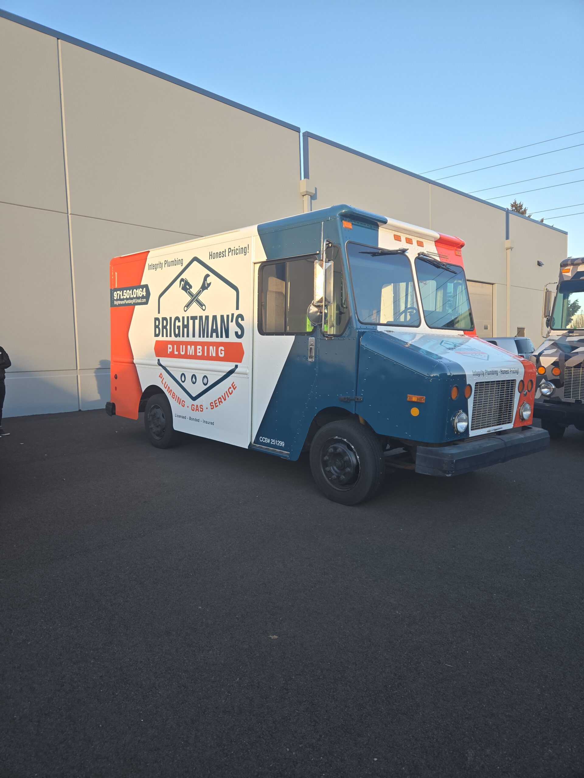 A Brightman's Plumbing service truck is parked outside a building on a paved lot, displaying the company logo and contact information on the side.